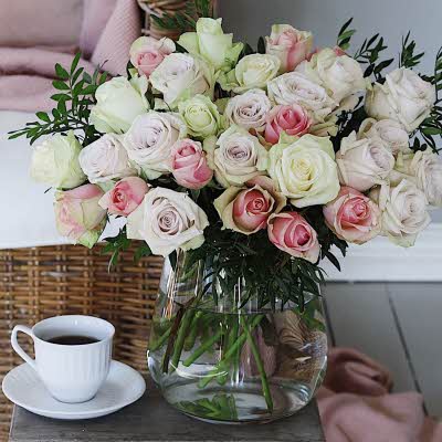 Kaffekopp ved siden av vase med blomster i