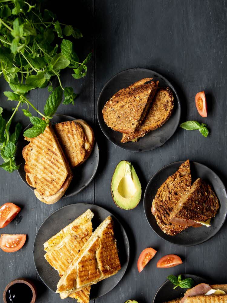Miljøbilde med fem tallerker med toast pyntet med avocado og tomater