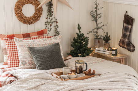 soverom dekorert i juletema med pynteputer, dyne, pledd, julesokk, juletre, julestjerne, julekrans