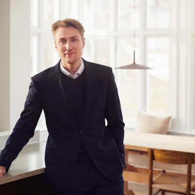 En mann som står og lener seg mot en benk i en leilighet
