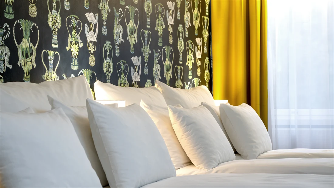 To dobbeltsenger, mønstrete tapet med grønne detaljer og gule gardiner i junior suite på Thon Hotel Linne.