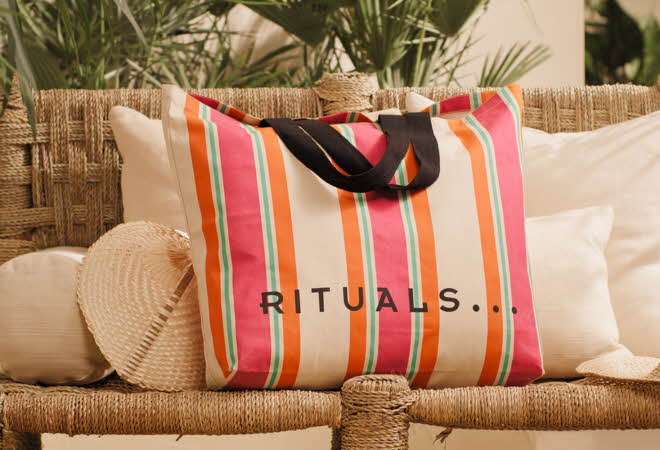 En Rituals strandbag som står på en krakk med puter