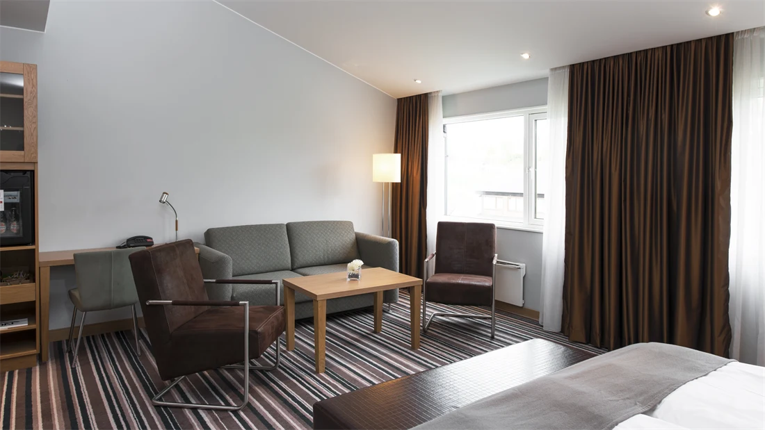 Stort rom med sofa, lenestoler, bord og dobbeltseng på standard room triple/family på Thon Hotel Vettre i Asker
