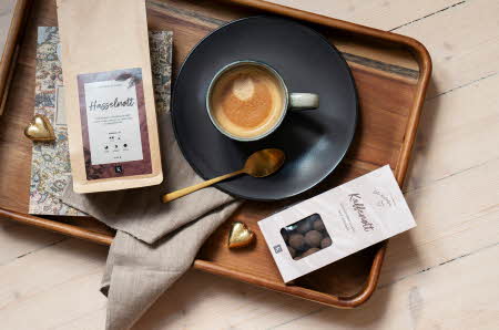 Et brett i tre med filtermalt kaffe, en kopp med kaffe og kaffenøtt sjokolade