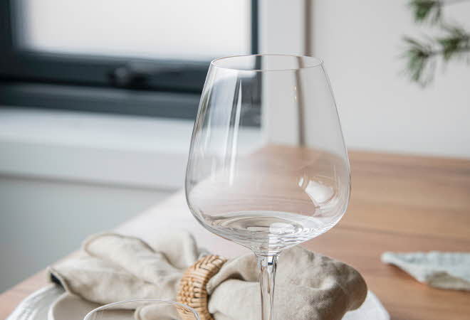 Et Odyssé glass fra Hadeland Glassverk står på et dekket bord.