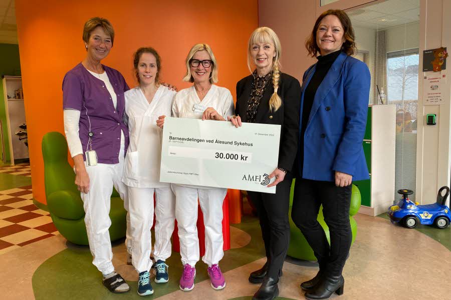 Fem damer holder en gaveskjekk til Barneavdelingen ved Ålesund sykehus