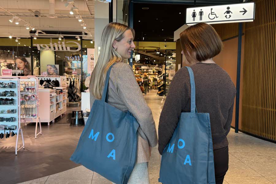 To damer som har hver sin blå Bokhahri handlepose over skuldra