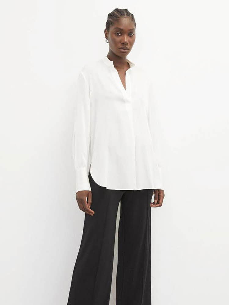 kvinnelig modell iført hvit bluse og svart dressbukse