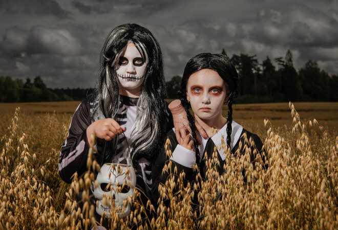 To jenter som står i en åker, en er kledd ut som et skjelett og den andre er kledd ut som Wednesday Addams