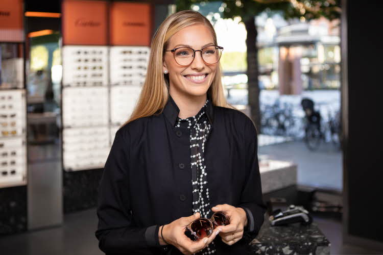 dame med briller i butikk med briller i hånden