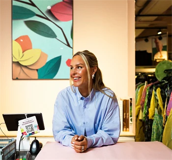 Kaja Sæther, eier av Qomo, står og lener seg på disken til en av butikkene hennes.