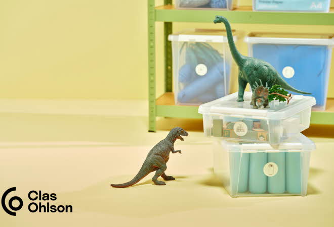 To oppbevaringsbokser med ting inne i, og tre miniatyr dinosaurer stående oppe på