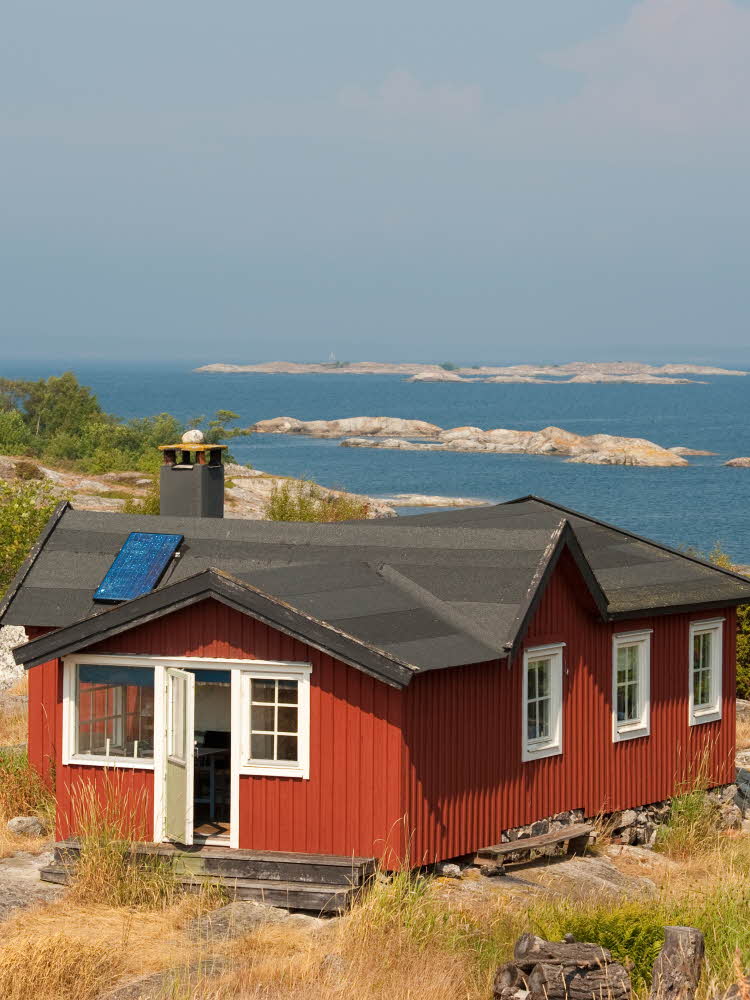 Rød hytte ved kysten, havet, svaberg, sommer.