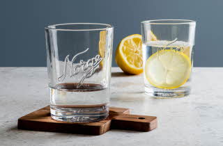 To Norgesglasset med vann, hvor den ene også inneholder en sitron.