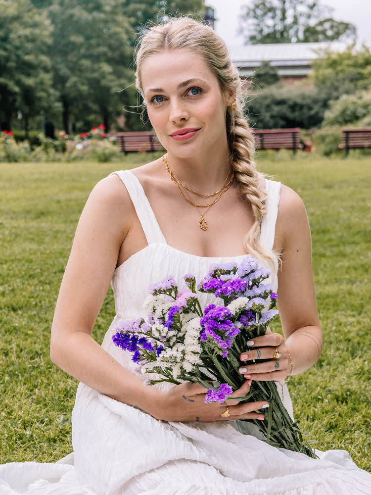 Dame i kjole som holder en blomsterbukett
