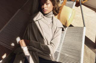 En kvinne i beige genser som ligger på en solseng.