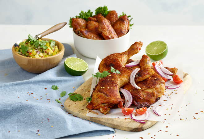 Grillede kyllingvinger på en skjærefjøl og i en hvit skål.