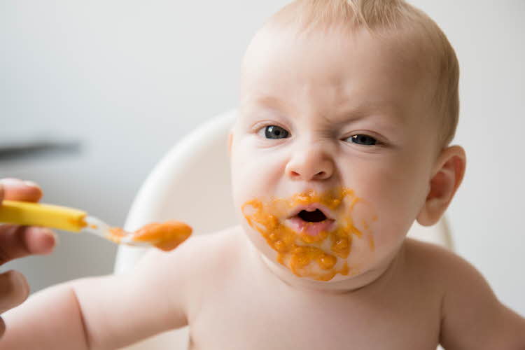 baby som spiser barnemat med grimase