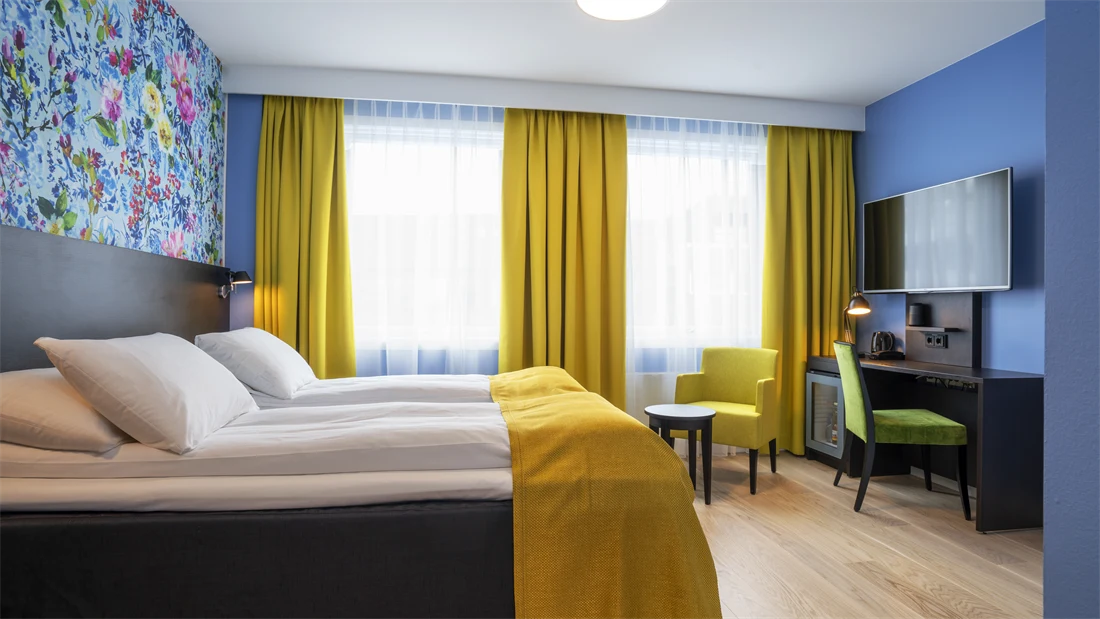 Separate senger, blomstrete tapet, gule gardiner og skrivebord i twin rom på Thon Hotel Moldefjord