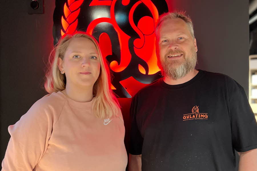 Dame og mann som smiler med gulating logo i bakgrunn