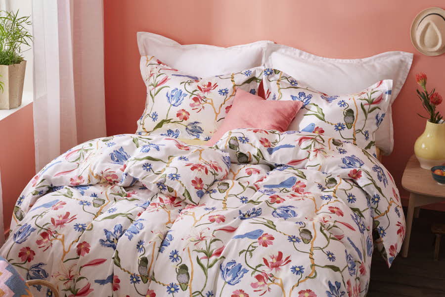 En seng med et blomstermønstret satengsengesett.