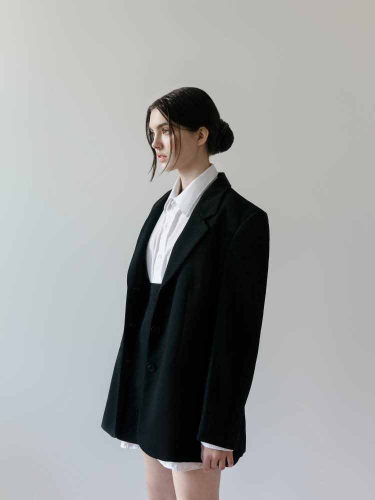 Dame med oppsatt hår, svart skjørt og svart oversized blazer