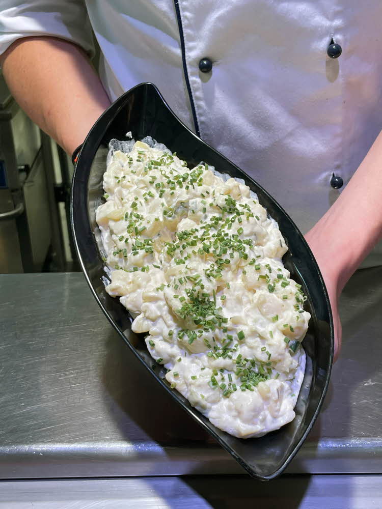 Mann holder opp en skål med potetsalat