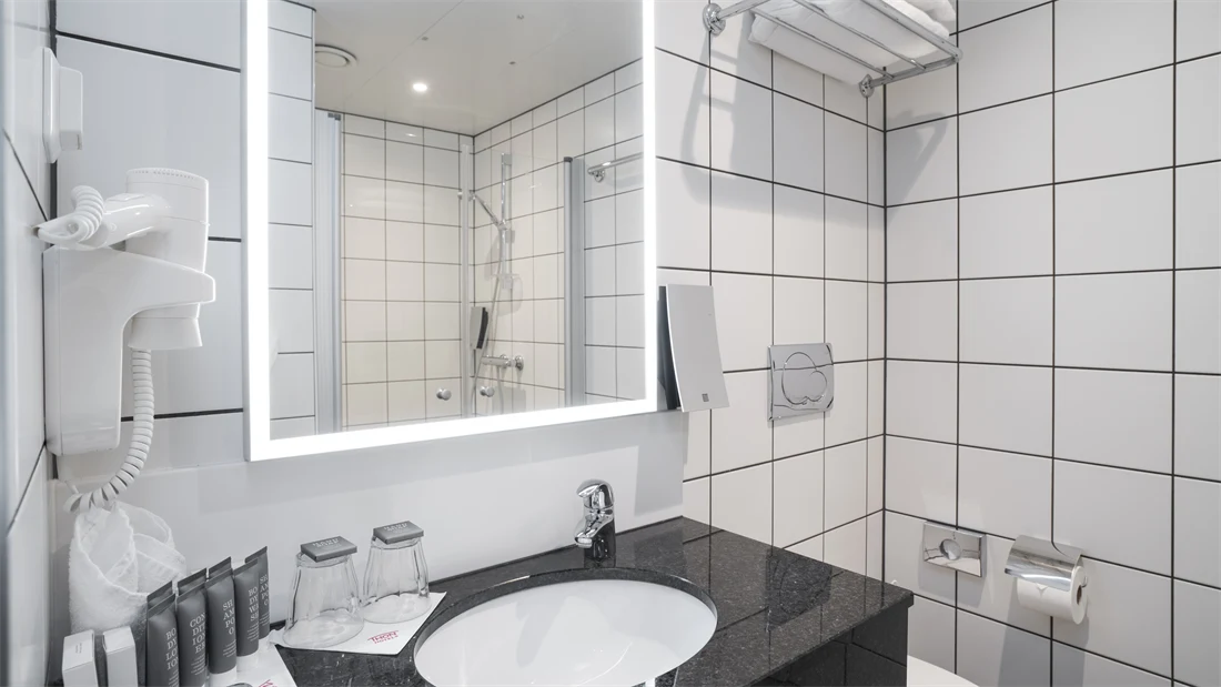 Servant i marmorbenk med toalettartikler og speil med led lys i bad på superior rom på Thon Hotel Kirkenes