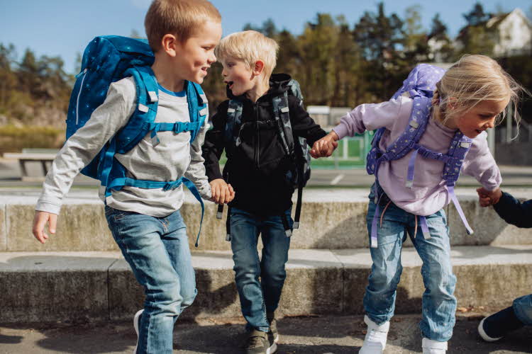 Barn med skolesekk løper