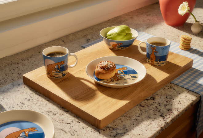 Kjøkkenbenk med to kaffekopper, en bolle med salat og en tallerken med bakverk på et trefat.