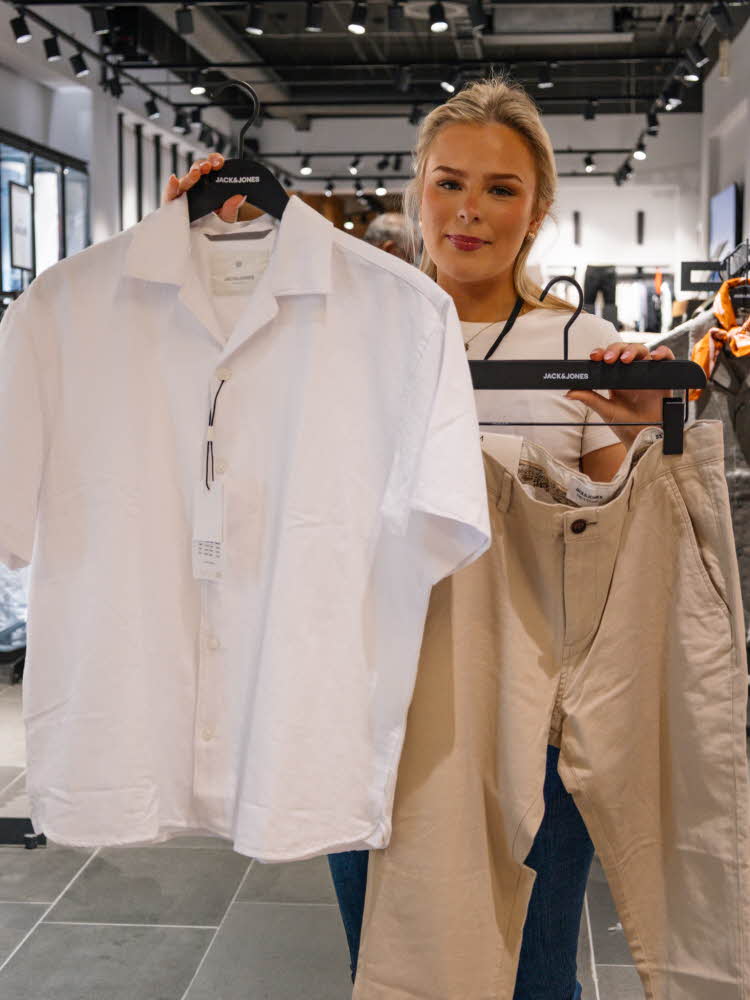 dame holder klessplagg til herre i butikk