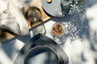 Et bord dekket med et grått servise, med en liten skål med nøtter ved siden av