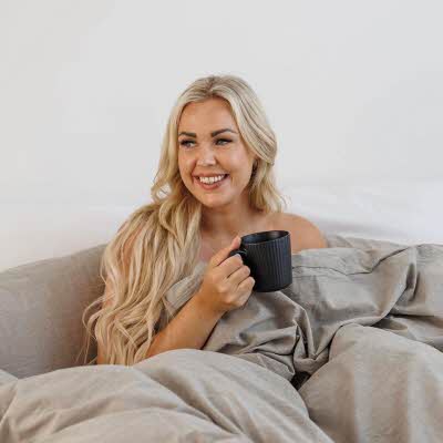 Kvinne med en kaffekopp i sengen