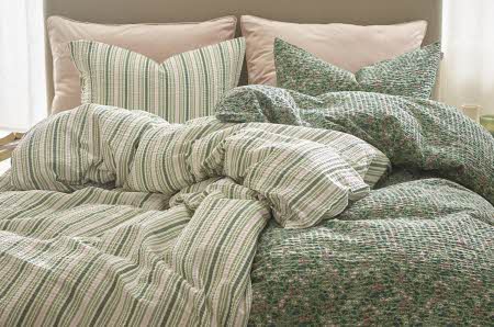 seng med en grønn sengetrekk med striper og en grønn sengetrekk med blomstrer