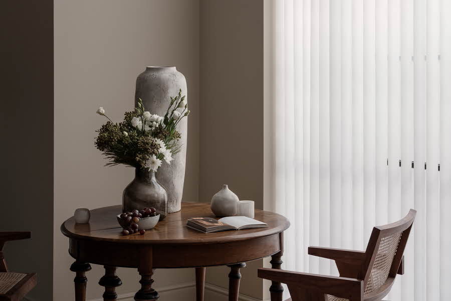 Et bord med en liten vase med blomster og en stor tom vase