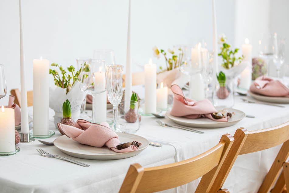 Langbord dekker til gjester med rosa servietter og grønn naturlig dekorasjon