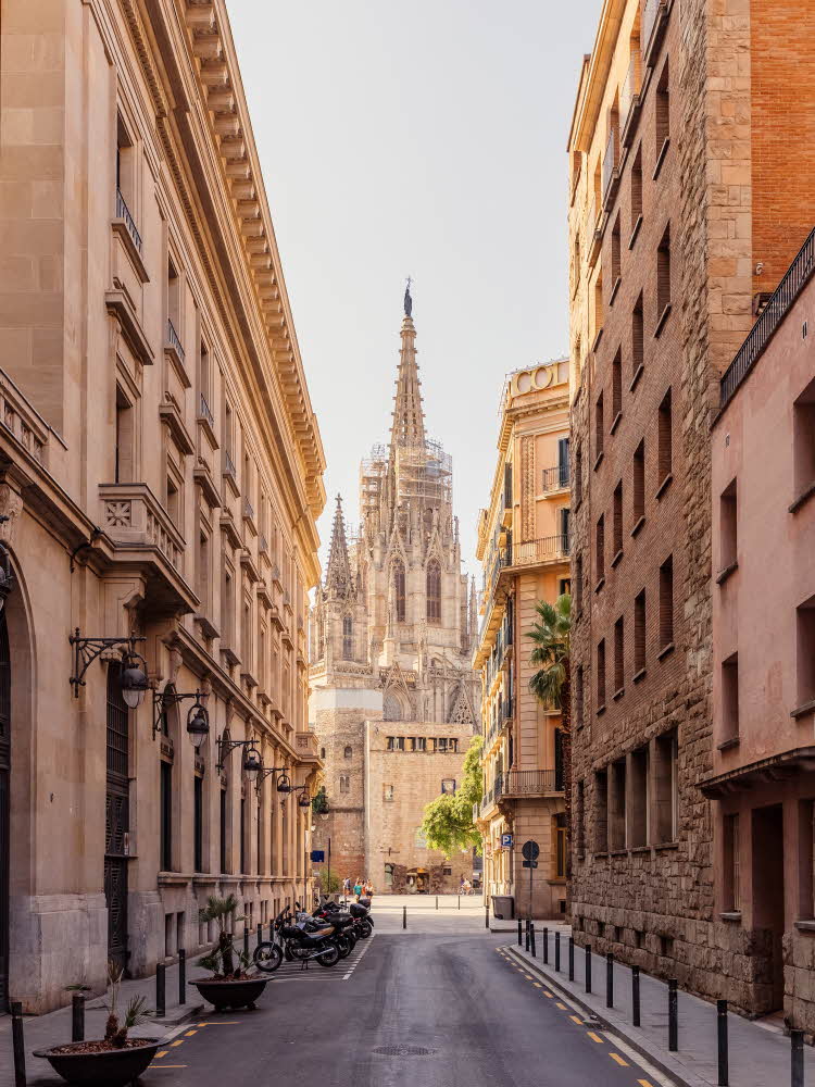 Barcelona by Sagrada Familia, blå himmel, storby. Barcelona, gater, smug, gotiske kvarter, Sagrada Familia Mann i by iført brun skjorte, beige chinos og flettet belte. Briller, ørepropper med kabel, mobil.
