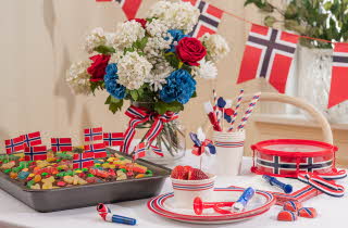 Et bord dekket til 17. mai, med masse norske flagg, en sjokoladekake og servise i rødt, hvitt og blått