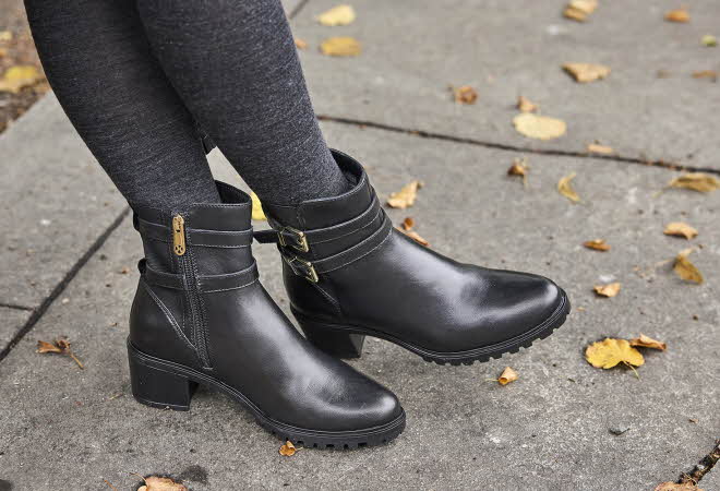 Svarte ankelstøvler med spenner og glidelås, brukt over mørke leggings på en høstlig fortau.