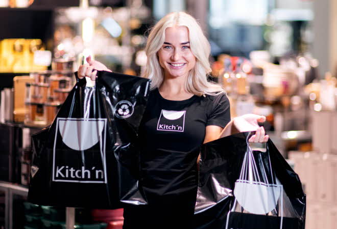 En jente som står og holder to poser fra Kitch'n