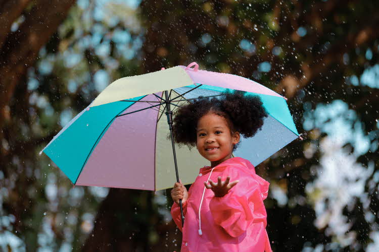 en jente som holder paraply og kledd i regnklær