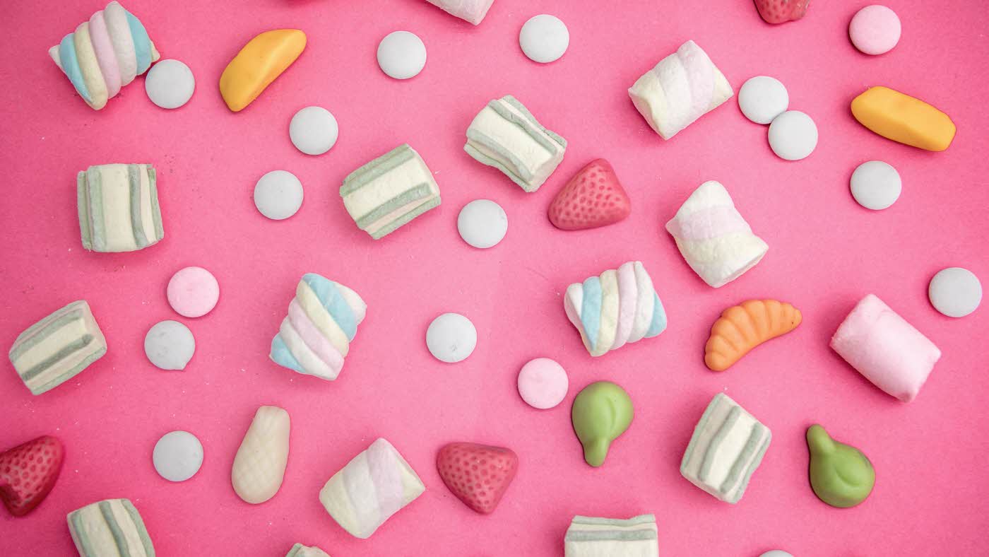 Godteri strødd omkring på rosa bakgrunn
