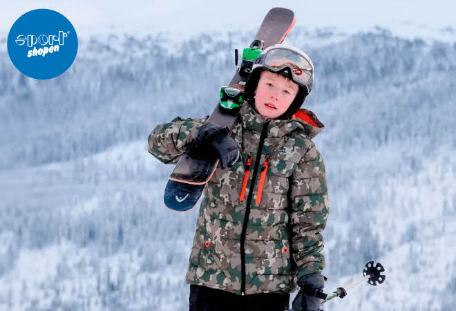 Et barn med Branäs jakke på, og slalomski over skulderen og hjelm på