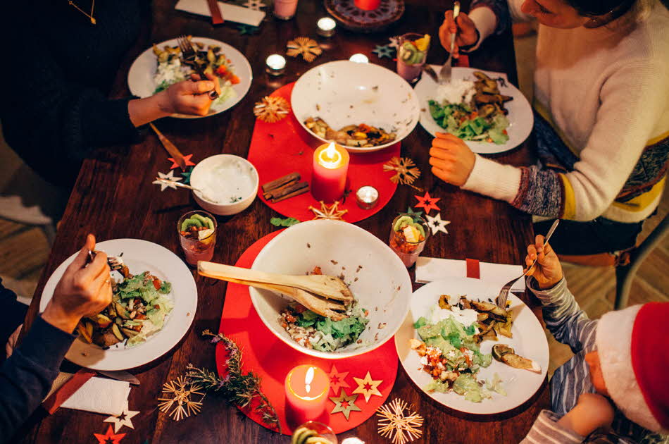 Folk som spiser vegetar julemiddag rundt et bord med rød duk