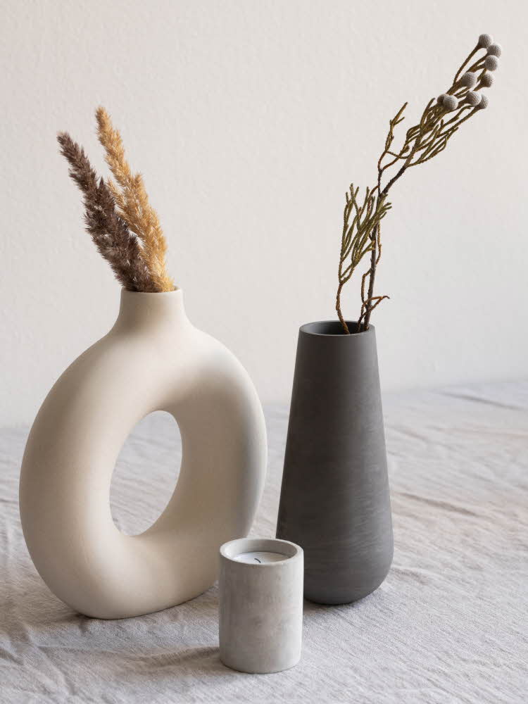 Tre vaser i matt betong på et bord med linduk