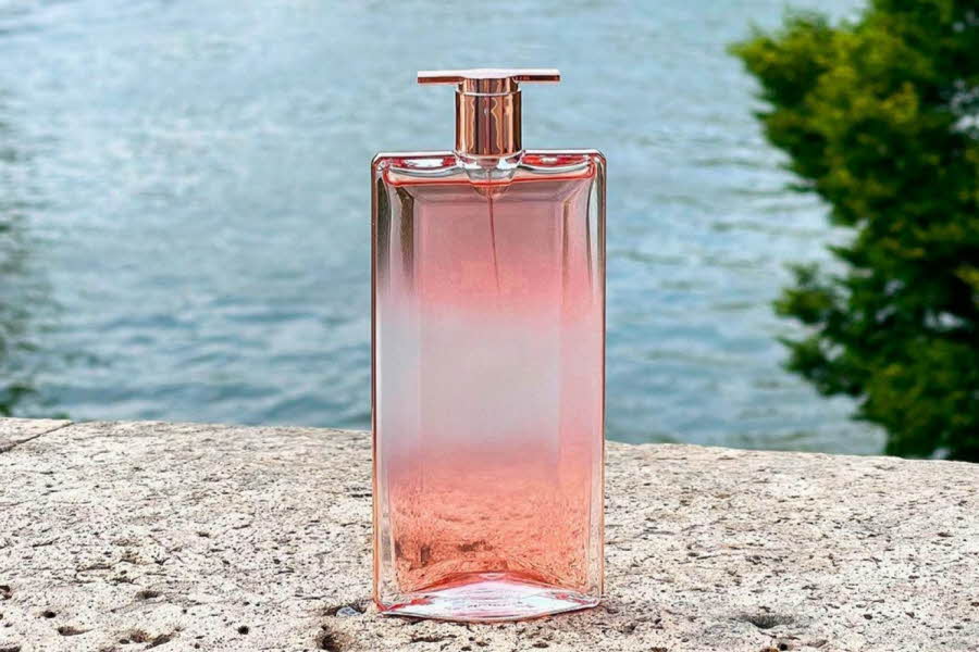Rosa parfyme står på en mur foran sjøen