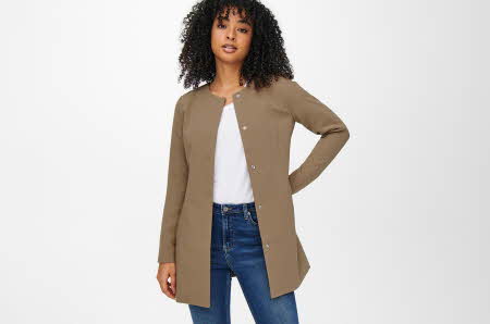 dame som poserer med brun kåpe, hvit t skjorte og blå jeans