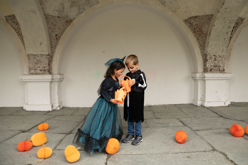 To barn som ser i en godteribøtte til halloween