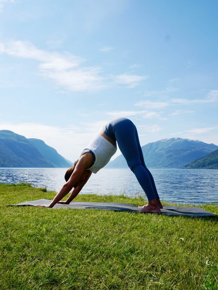 anny johansen viser yogaøvelser foran vakker fjord