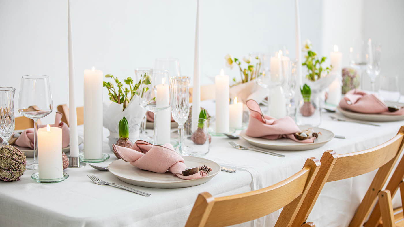 Langbord dekker til gjester med rosa servietter og grønn naturlig dekorasjon